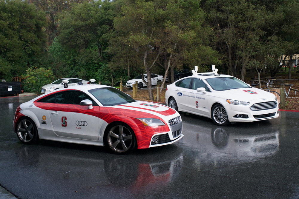 Autonome Testfahrzeuge von Autoherstellern, die eine Partnerschaft mit dem CARS haben. Der Audi TT mit dem Namen „Shelly“ im Vordergrund kann ohne Fahrer mit Renngeschwindigkeit auf Rennstrecken fahren. Der Ford Fusion im Hintergrund kann auch ohne Fahrer hervorragend driften.